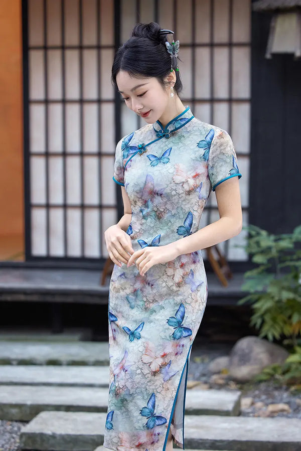 Woman wearing a traditional Chinese Blue Midi Length Qipao Dress with Butterfly and Floral Print  with butterfly design outdoors.