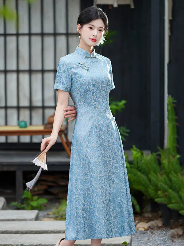 Woman in a blue Modern Floral Short Sleeve A-Line Qipao Dress standing outdoors with greenery and a building in the background
