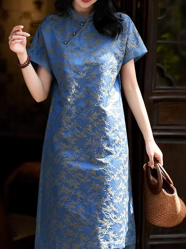 Woman wearing a blue lace Blue Modern Silk-Cotton Blend Jacquard A-Line Loose Qipao dress holding a brown bag indoors.