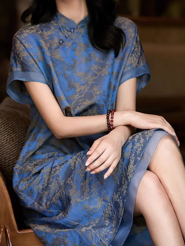 Woman wearing a Blue Modern Silk-Cotton Blend Jacquard A-Line Loose Qipao  dress with floral patterns sitting on a chair.