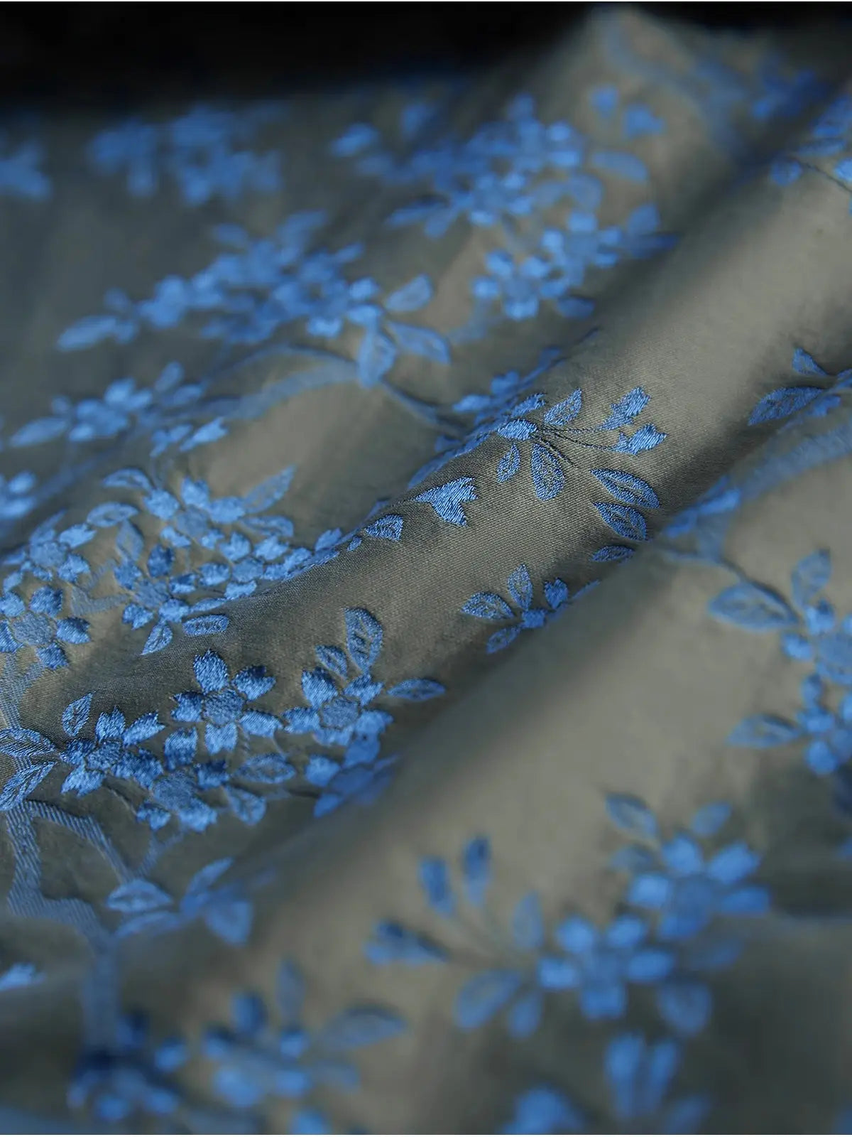 Close-up of fabric with blue floral embroidery on a dark background