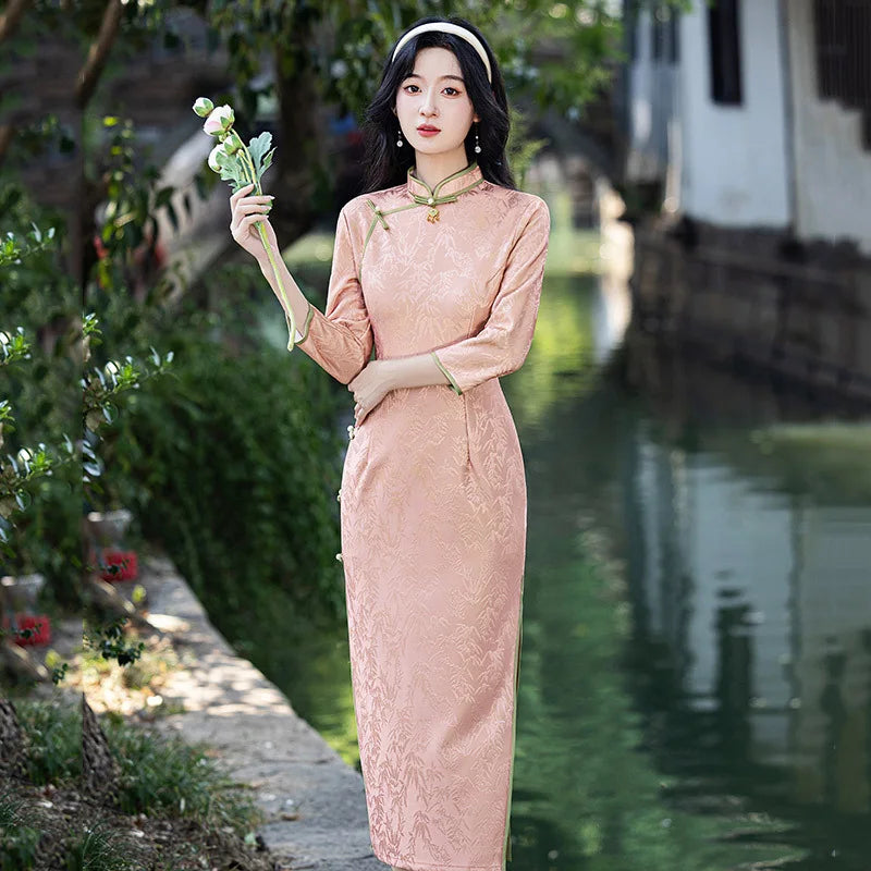 Woman in a traditional Blush Pink Long Sleeves Qipao Cheongsam Dress with Bamboo Pattern holding flowers by a canal