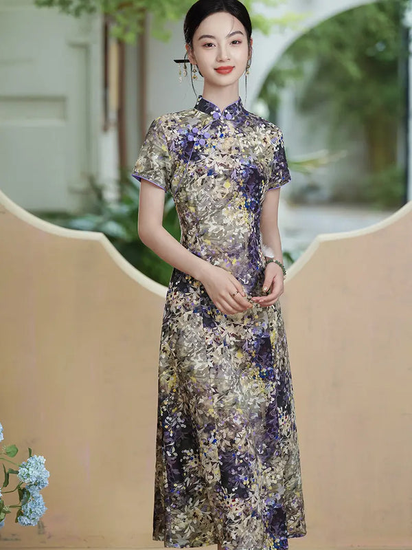 A woman wearing a short-sleeved Botanical Violet & Olive Floral Jacquard Modern A Line Qipao cheongsam dress in purple, gold, and beige tones, standing in front of a beige decorative wall with a blurred outdoor background.