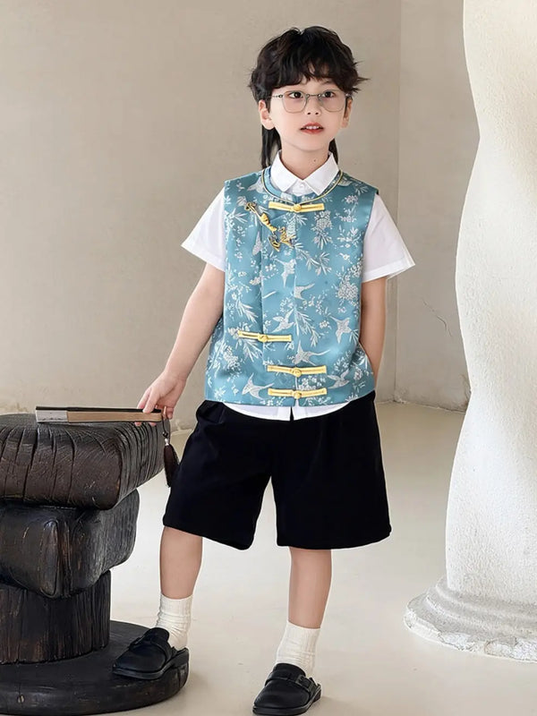 Child wearing a floral Boys' Traditional Chinese Style Blue Vest & Shorts Outfit  over a white shirt with black shorts, standing indoors.