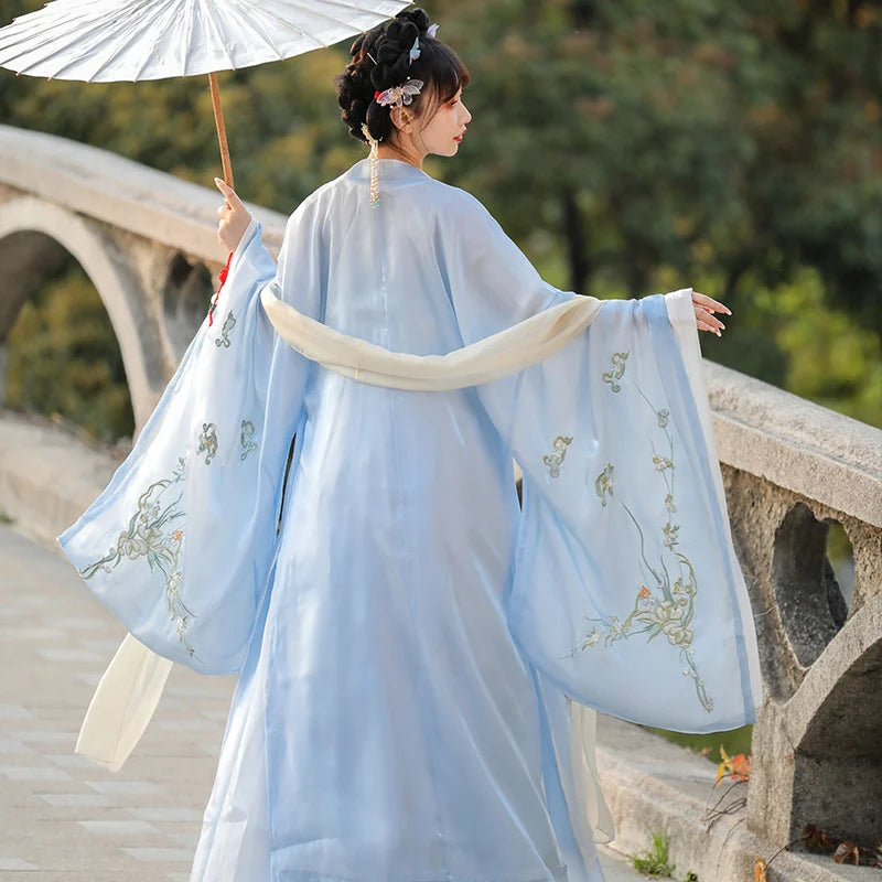 Woman in traditional light blue Chinese Tang Dynasty Ruqun Set Hanfu Dress with floral patterns standing on a stone bridge.
