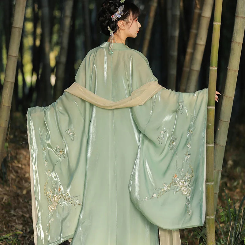 Woman in a light green traditional Chinese Tang Dynasty Ruqun Set Hanfu outfit with floral embroidery standing among bamboo.