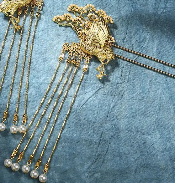 Decorative gold Chinese Wedding Crane Hairpin   with pearl pendants on a textured blue fabric background