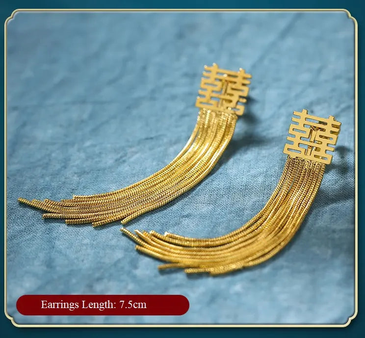 Gold double happiness earrings with intricate design on a textured blue background
