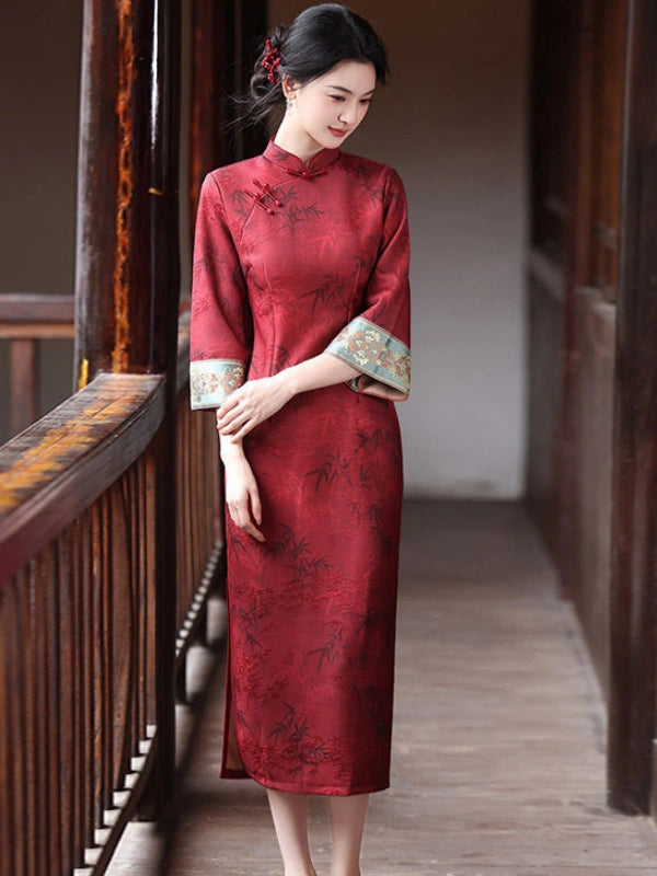 A woman wearing a Crimson Red Bamboo Jacquard Long Sleeve Qipao With Embroidered Cuff , standing in a traditional wooden corridor.