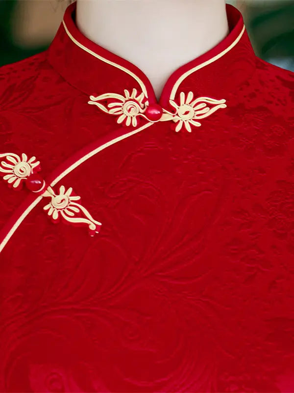 Close-up of a red embroidered traditional Chinese cheongsam jacket on a mannequin, featuring gold floral frog closures and a matching red-and-gold collar.