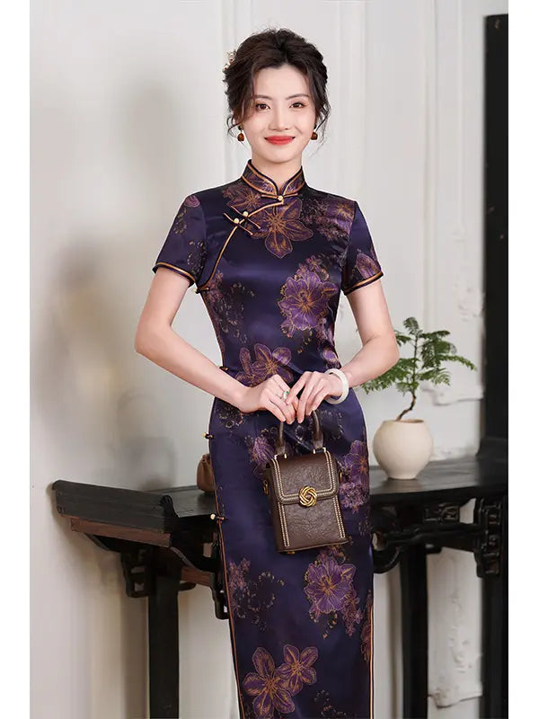 Woman in a traditional Deep Amethyst Purple & Gold Floral Silk Long Qipao dress holding a handbag indoors.