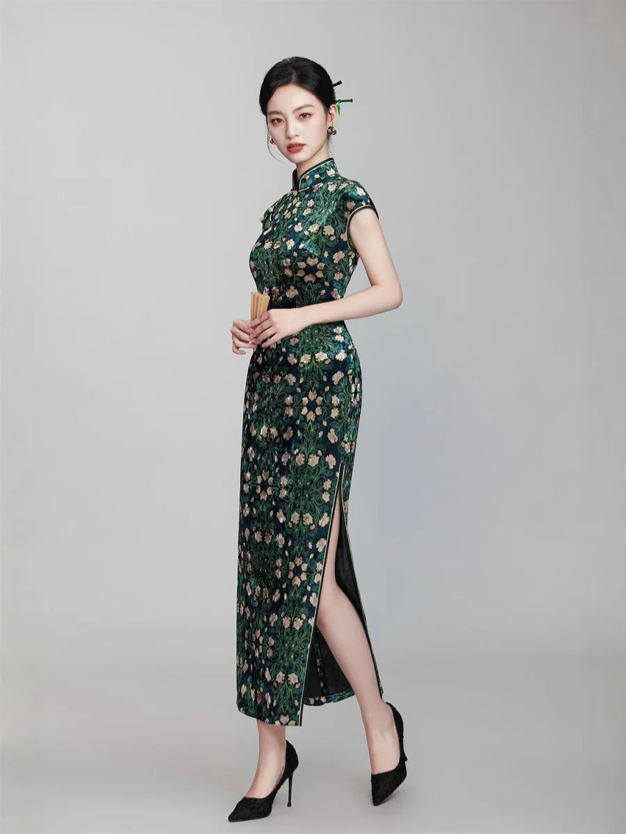 Woman wearing a Deep Green Floral Cap Sleeves Long Qi pao Dress with a high slit on a gray background
