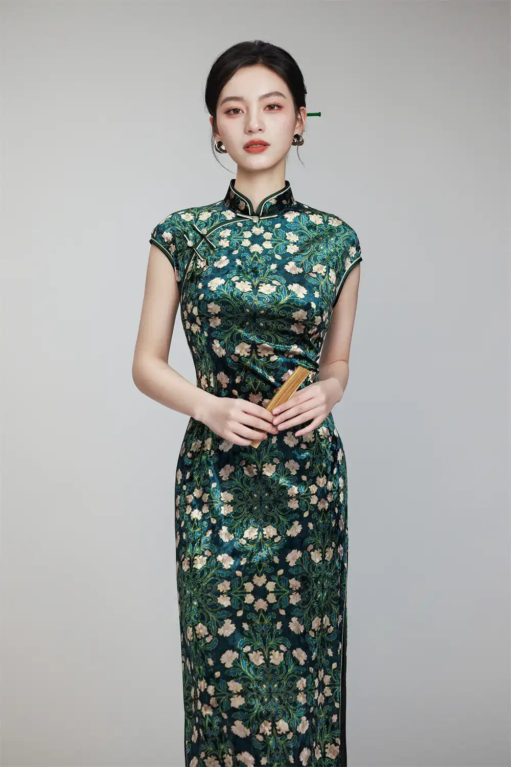 Woman wearing a Deep Green Floral Cap Sleeves Long Qipao Dress against a gray background
