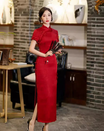 Woman in a Deep Red Floral Long Qipao Cheongsam Dress with Lace Trim holding fans indoors with decorative elements.