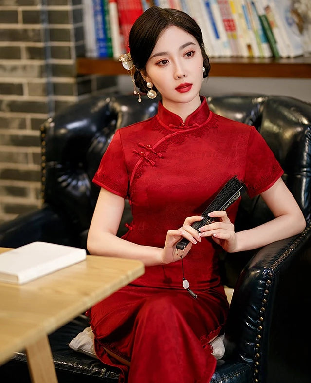 Woman in a traditional Deep Red Floral Long Qipao Cheongsam Dress with Lace Trim outfit sitting in a room with books on shelves.
