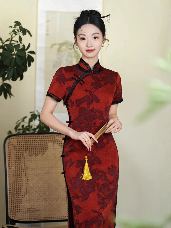 Woman wearing a rDeep Red Floral Qipao Cheongsam Dress with Black Trim, holding a yellow object indoors.
