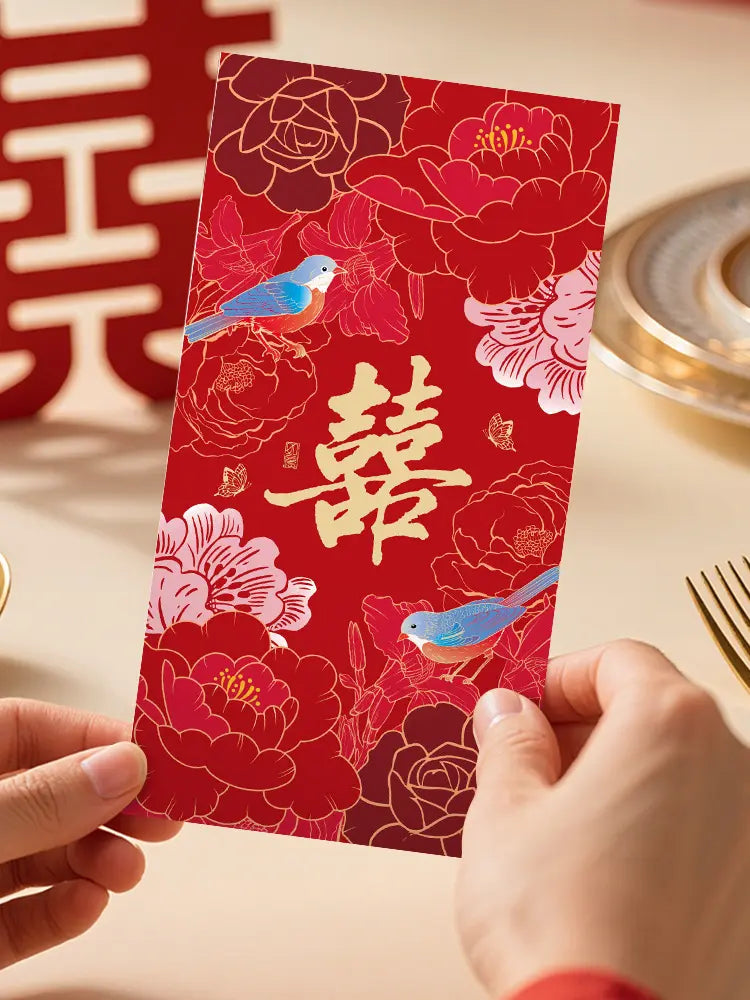 Double Happinese Floral Chinese Wedding Red Envelopes   with floral and bird design held by a hand on a light background