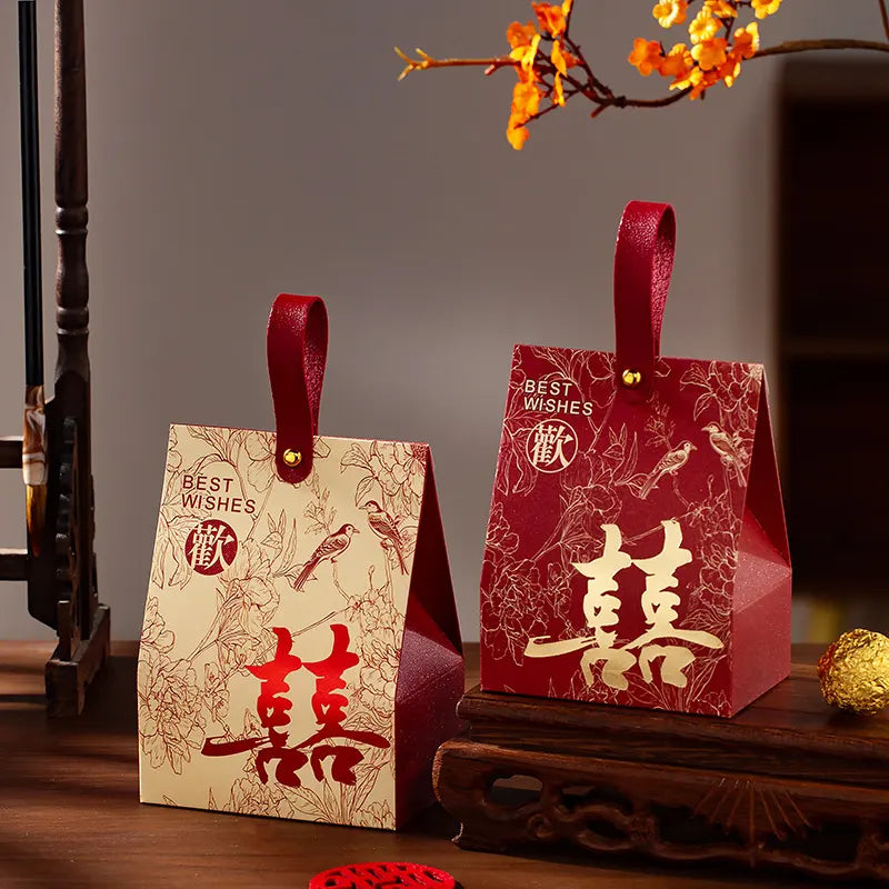 Two red  Double Happiness Chinese Wedding Favor Box with gold text and designs on a wooden surface.
