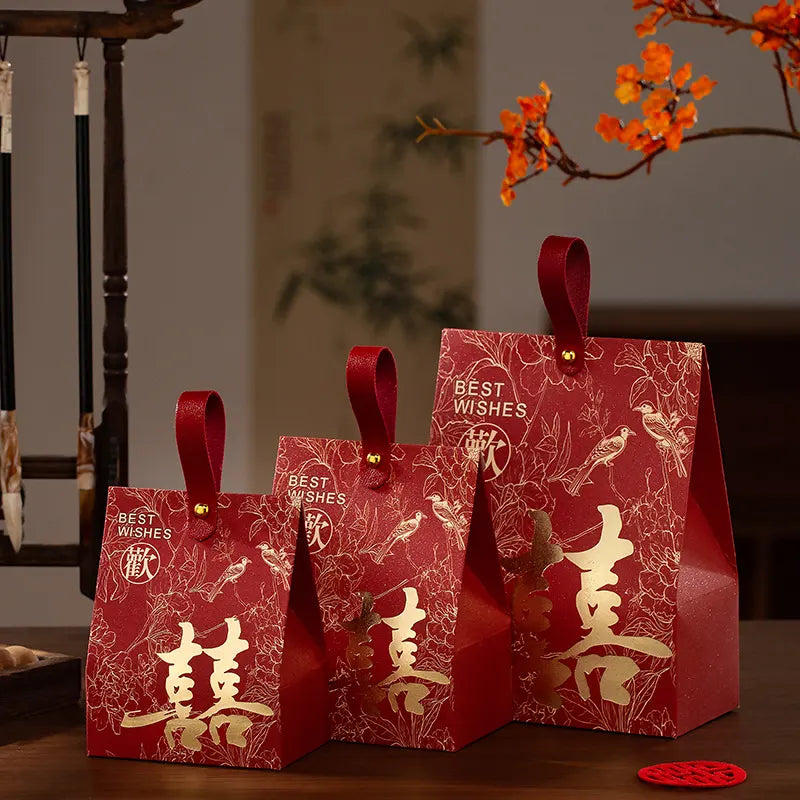 Three red  Double Happiness Chinese Wedding Favor Box  with gold text and designs on a wooden surface.