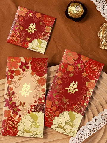 Three Double Happiness  Floral Wedding Red Envelopes  with gold text on a textured surface.