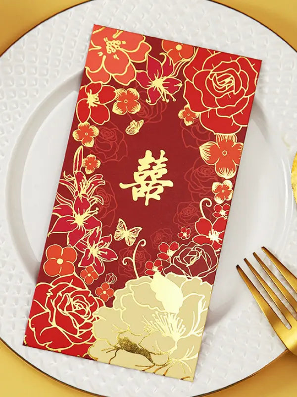 Double Happiness  Floral Wedding Red Envelopes with gold floral patterns and Chinese characters on a white plate with a gold fork.
