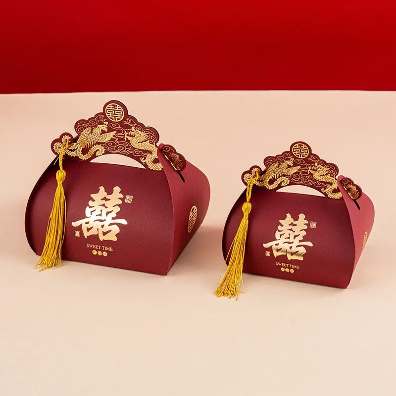 Two red Dragon & Phoenix Double Happiness Chinese Wedding Favor Boxes with gold designs and tassels on a beige background