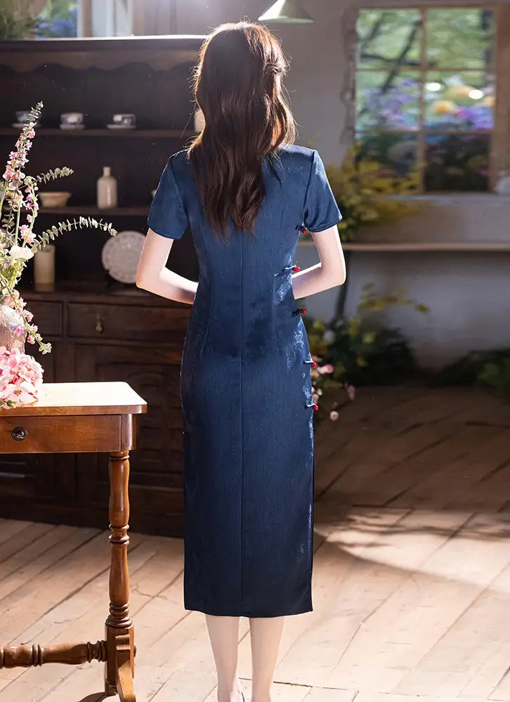Woman in a bElegant Blue Jacquard Butterfly Cheongsam – Mid-Length Modern Qipao  standing in a sunlit room with wooden floor and decorative items.