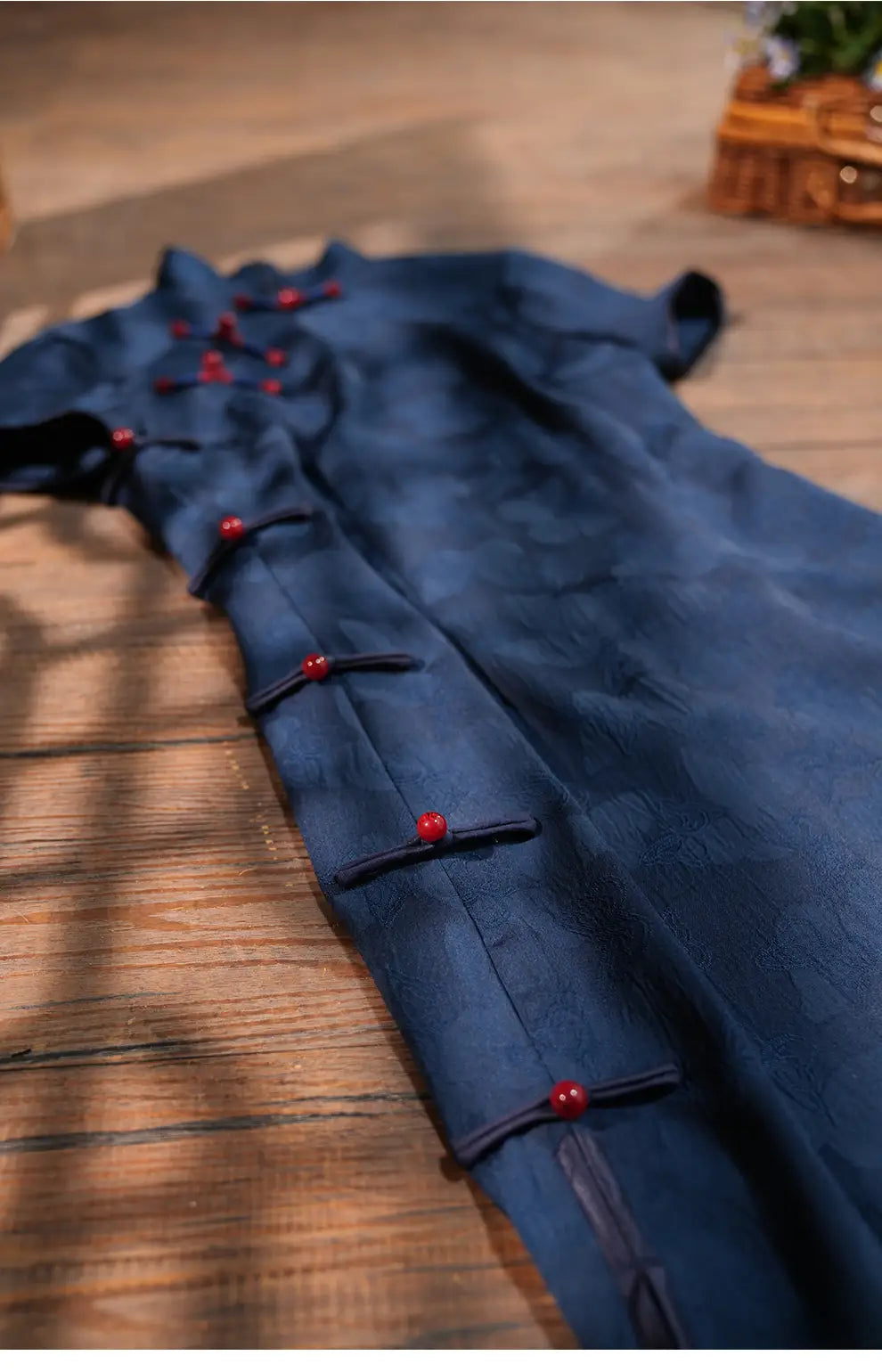 Elegant Blue Jacquard Butterfly Cheongsam – Mid-Length Modern Qipao  with red buttons on a wooden surface