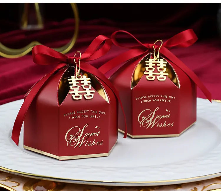 Red chinese Wedding Favor Boxes with Double Happiness Charm with gold accents and ribbons on a white plate.