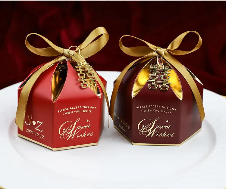 TwoElegant Wedding Favor Boxes with Double Happiness Charm  with gold ribbons and 'Sweet Wishes' text on a white surface.