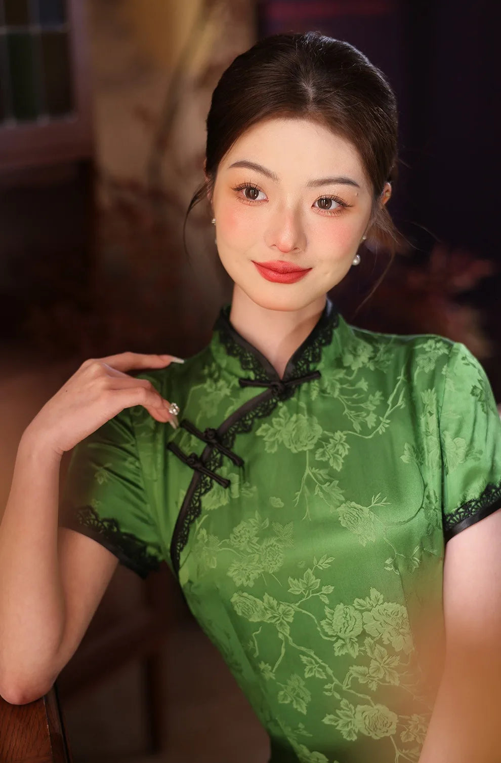 Woman wearing a Emerald Forest Green Silk-Blend Qipao with Lace Trim  traditional outfit with a blurred background