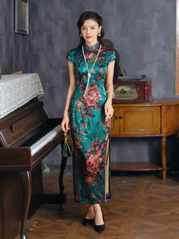 Woman in a floral silk chinese qipao dress standing in a room with a piano and wooden furniture.