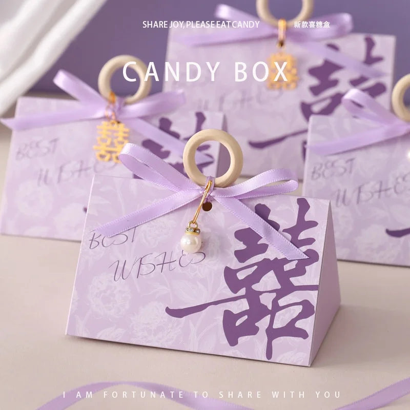 Purple Floral Triangular Shape Double Happiness Favor  candy box with decorative ribbons and charms on a light background