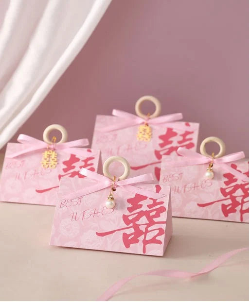 Pink Floral Triangular Shape Double Happiness Favor Boxes gift boxes with Chinese characters and decorative ribbons on a pink background