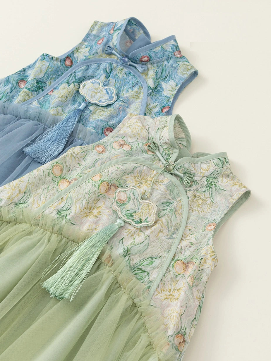 Two sleeveless traditional Chinese-style dresses laid flat on a light cream background. The top dress is light blue with floral embroidery and a blue tassel, and the bottom dress is pale green with floral embroidery and a green tassel.