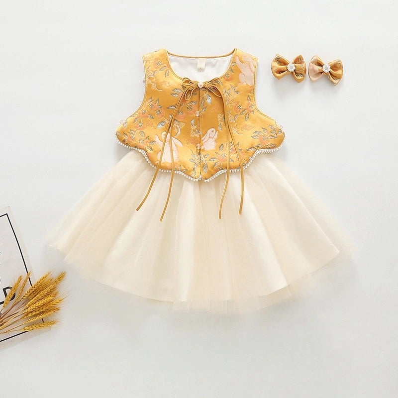 A baby girl's sleeveless Golden Brocade Vest & Tulle Chinese Baby Princess Dress   with a mustard yellow embroidered bodice and a cream tulle skirt, styled with two matching bow headbands on a light gray background.