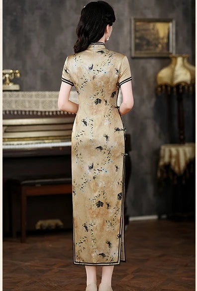 Woman wearing a Golden Mulberry Silk Qipao Dress with Black Floral Print  in an indoor setting with a piano and decorative items.