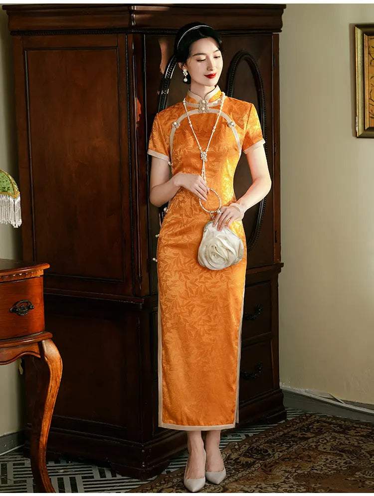 Woman in an  traditional Golden  orange Chinese  long cheongsam dress standing in a room with wooden furniture.