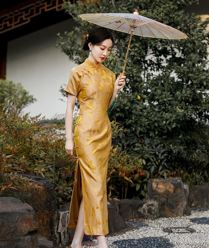 A chinese girl in  long gold silk cheongsam with  intricate floral and bird jacquard patterns