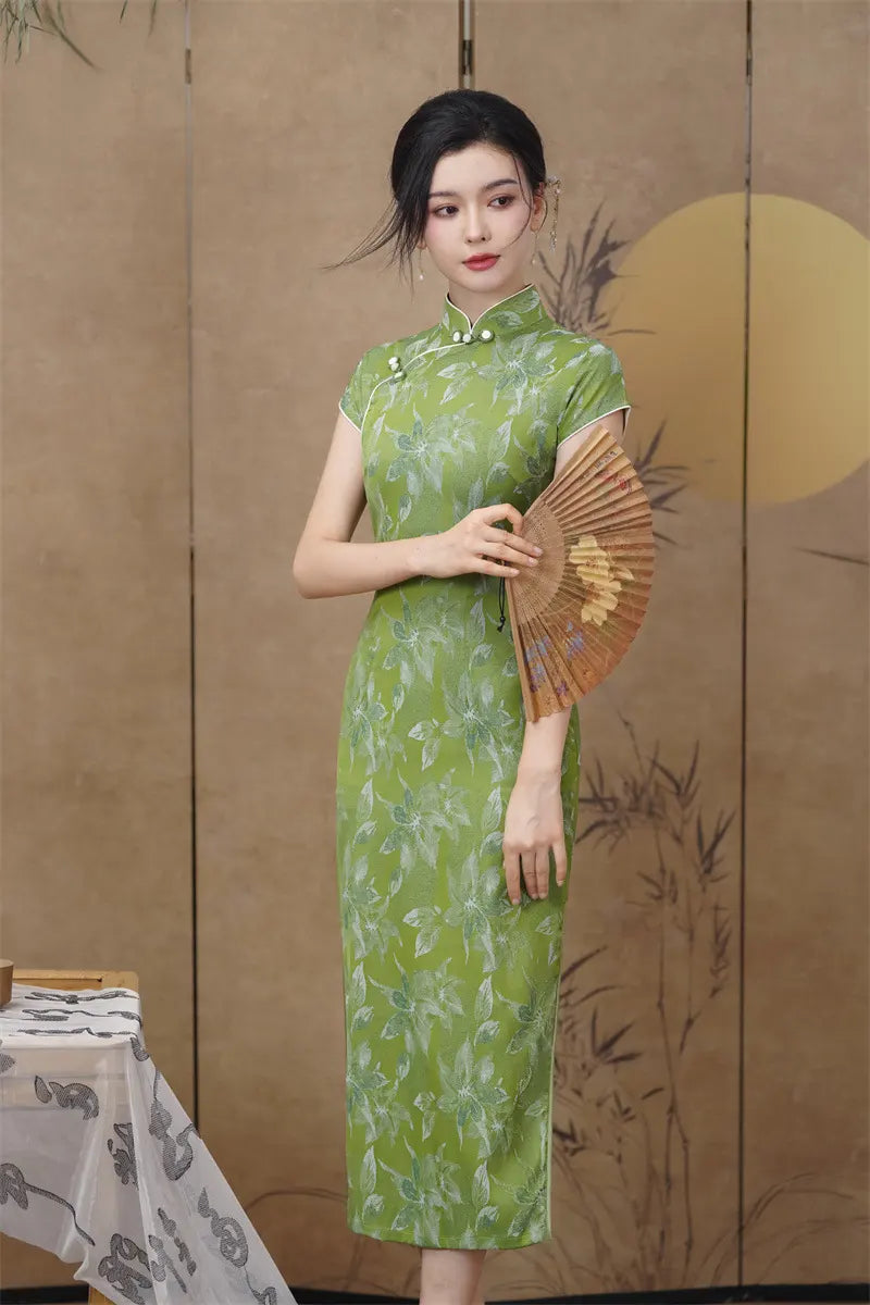 Woman in a Green Floral  Cap Sleeve Modern Qipao Cheongsam Dress  holding a fan against a wooden panel background