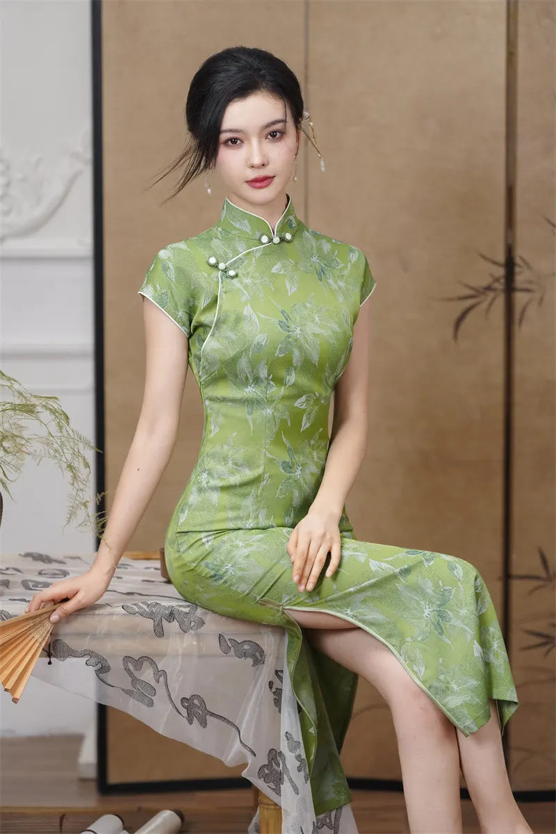 Woman in a Green Floral  Cap Sleeve Modern Qipao Cheongsam Dress sitting on a table with a decorative background