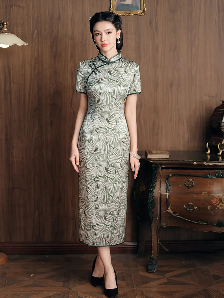 Woman in a Green Leaf Print Silk Long Qipao Dress standing in a room with wooden walls and furniture.