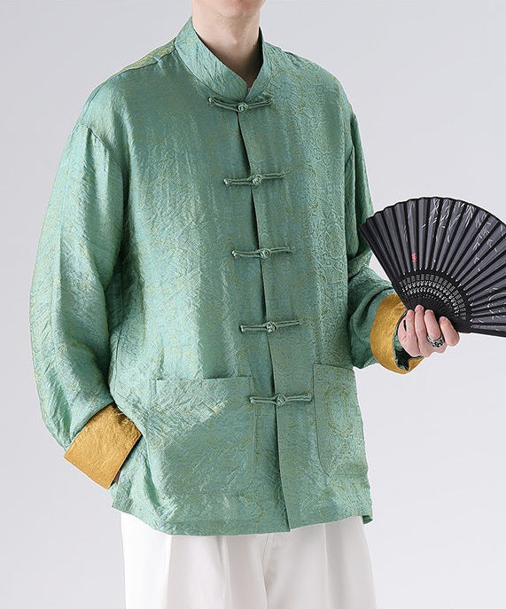 Person wearing a green traditional Men's Oriental Jacquard Kung Fu Tang Shirt holding a black fan on a white background