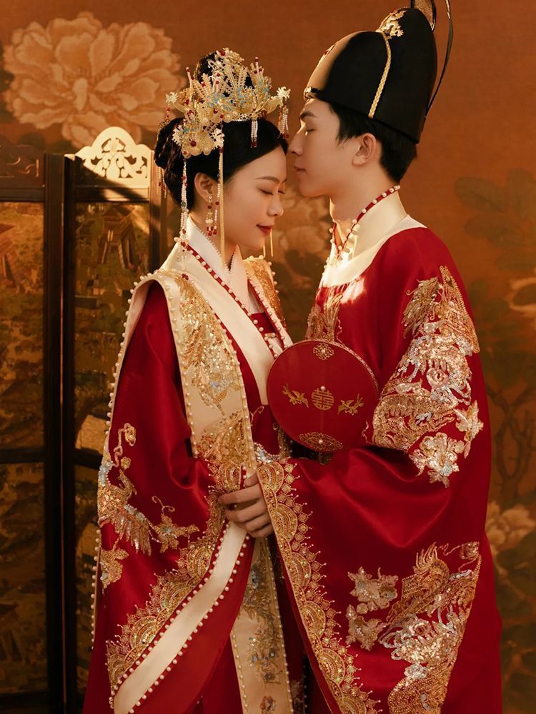 Couple in traditional Chinese Ming Dynasty wedding hanfu attire with intricate designs and gold accents.