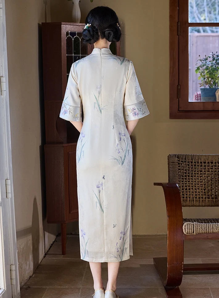 Woman wearing a Ivory Floral Jacquard Qipao Dress with Embroidery  in a room with wooden furniture and a window.
