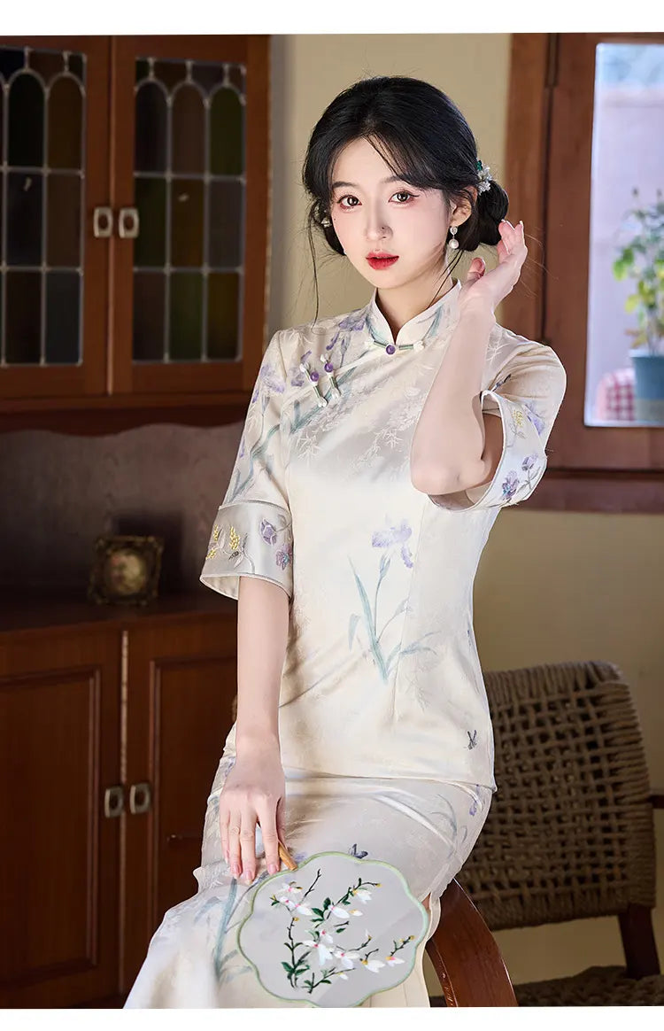 Woman in a traditional Chinese Ivory Floral Jacquard Qipao Dress with Embroidery outfit holding an embroidered fan indoors.