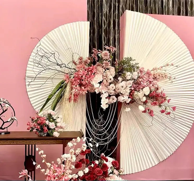 Decorative wall with white fans and pink floral arrangements against a pink background