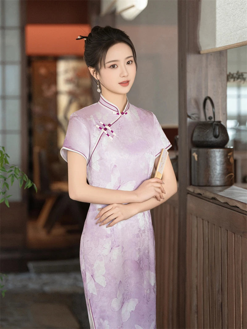 Woman in a traditional light purple Lavender Butterfly Print Midi Cheongsam Dress  with floral patterns in a warm-toned interior setting.