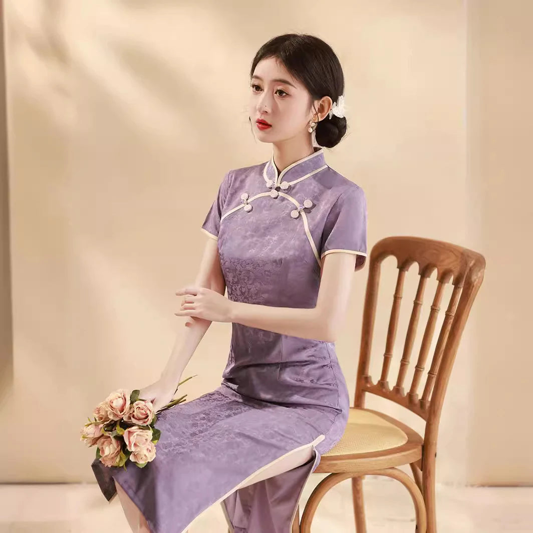 Woman in a purple Lavender Floral Short Sleeves Jacquard Qi pao Dress  sitting on a wooden chair holding flowers against a beige background