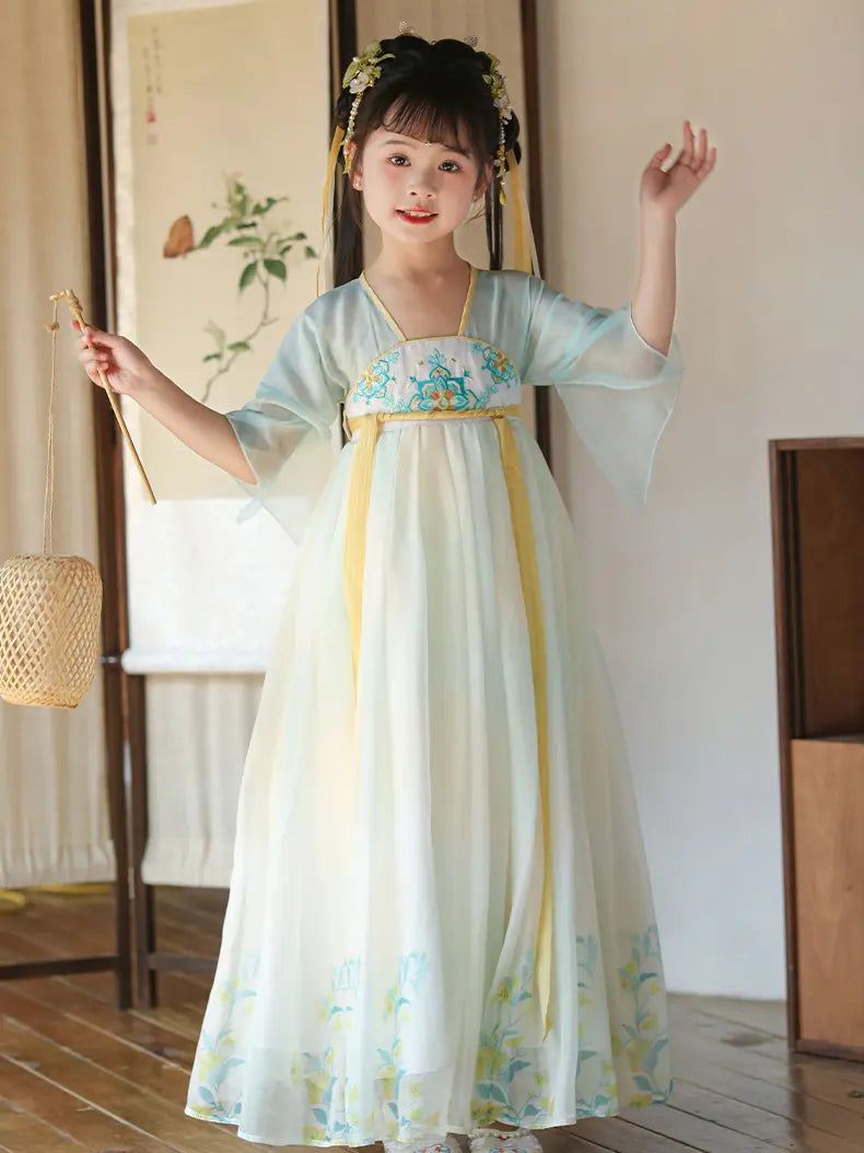 Young girl in a traditional Light Blue Girls Chinese Tang Dynasty Style Fairytale Hanfu Dress  outfit with floral patterns in a room with wooden flooring and a lamp.